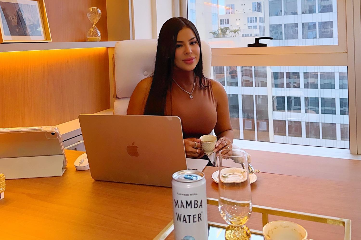 Gabriele Moutinho na mesa de atendimento, com vista para a Barra da Tijuca