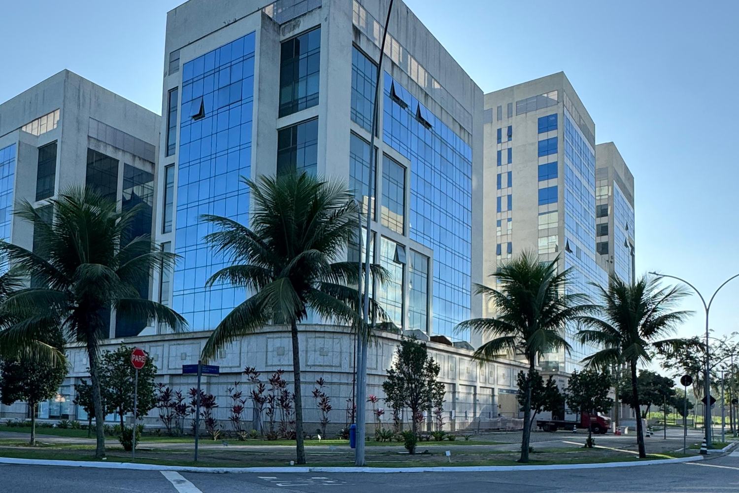 Fachada do One World Offices, com palmeiras na entrada